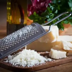Tarka z grudkami sera, obok kawałki Grana Padano i parmezanu, gotowe do starcia.