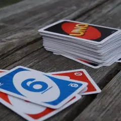 Karty UNO leżą na drewnianym stole. Czas na grę i poznanie uno flex zasady!