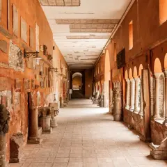 Corridoio con reperti antichi, un'idea di cosa vedere a Trastevere. Colonne, iscrizioni e frammenti decorano le pareti arancioni.