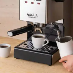 Jaka kawa do ekspresu kolbowego? Świeżo zaparzony espresso w filiżance, obok dzbanek do mleka.