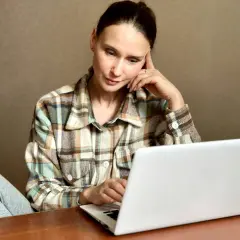 Kobieta zamyślona przy laptopie szuka informacji, jak usunąć negatywny wpis w BIK.