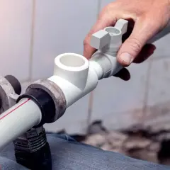 Instalator pokazuje, jak łączyć rury plastikowe do wody, montując trójnik.