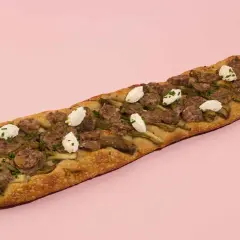 Deliciosa coca de recapte con salchicha, alcachofas y queso de cabra, lista para compartir.