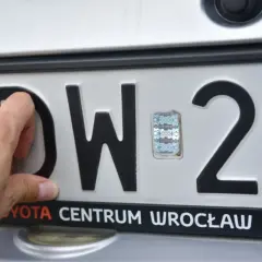 Ręka dotyka litery D na tablicy rejestracyjnej DW 29. Tst rejestracja w Toyota Centrum Wrocław.