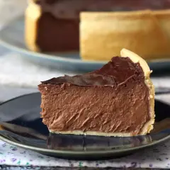 Rebanada de flan de chocolate con cobertura brillante, servida en plato oscuro.