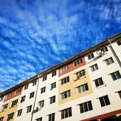 Kolorowy blok mieszkalny pod błękitnym, pofalowanym niebem. Może to być miejsce, gdzie ktoś składa wniosek o mieszkanie komunalne.