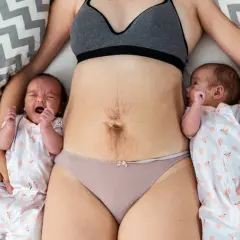 Maman avec ses jumeaux, le ventre marqué par la grossesse, évoquant la pesanteur périnée après accouchement.