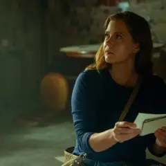 Une femme examine des photos dans un sous-sol sombre, peut-être liée à la série "Cape Fear".
