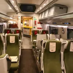 Wnętrze wagonu PKP Intercity. Zielone siedzenia bez gwarancji miejsca do siedzenia czekają na pasażerów.
