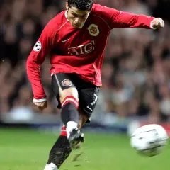 Cristiano Ronaldo w czerwonej koszulce Manchesteru United, z numerem na koszulce, kopie piłkę.