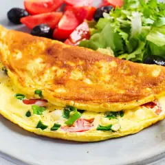 Złocisty omlet z warzywami i sałatką na talerzu.