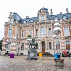 Devant un château, des sphères argentées, comme des habits de lumière, scintillent sur des structures métalliques, entourant une statue équestre.