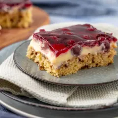 Ein Stück saftige Kirschtorte mit Pudding und Kirschen, bedeckt mit rotem Tortenguss.