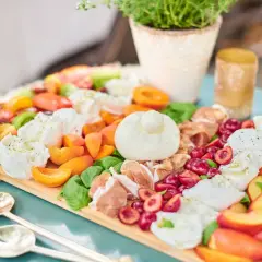 Antipasti-Platte mit Kerze, Wurst, Käse, Oliven und Brot auf Holztisch.
