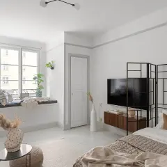 Przytulne mieszkanie bezczynszowe z wygodną kanapą przy oknie, łóżkiem i telewizorem.
