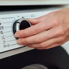 Dłoń kręci pokrętłem pralki Whirlpool. Rozwiązywanie problemów z instrukcją obsługi.