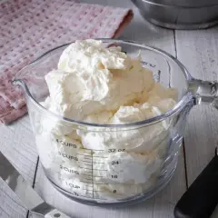 Ein Messbecher gefüllt mit luftiger Swiss Meringue Buttercreme, bereit für süße Kreationen.
