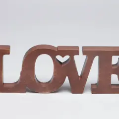 Letras de madera marrón forman la palabra "LOVE", con un corazón tallado en la "O".