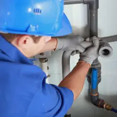 Instalator montuje odpowietrzenie kanału sanitarnego w domu parterowym, łącząc rury.