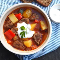 Gęsty, aromatyczny bogracz z wołowiną, ziemniakami i papryką, udekorowany kleksem śmietany.