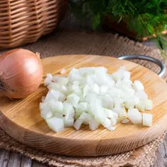 Cipolla intera e tritata su tagliere di legno. Un rimedio naturale per come togliere l'odore di aglio dalla bocca.