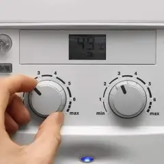 Ręka ustawia pokrętło pieca gazowego dwufunkcyjnego De Dietrich. Cyfrowy wyświetlacz pokazuje 49°C.