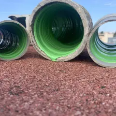 Trois tuyaux en PVC, dont un avec un revêtement vert vif, prêts pour enlever calcaire canalisation pvc.