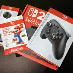 Pudełka z akcesoriami do Nintendo Switch: kontroler Pro, karta microSD 256 GB z Mario i kamera.