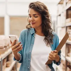 Kobieta z telefonem i teczką w magazynie pełnym ceramiki. To jej milenium dla firm, czas na rozwój i nowe zamówienia.