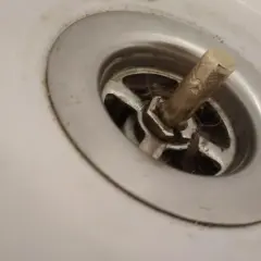 W umywalce widać wciśnięty korek, wokół którego zebrały się włosy i brud.