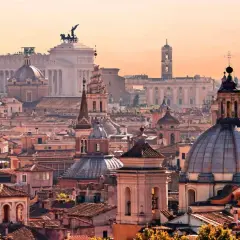 Panorama di Roma al tramonto, con cupole e monumenti iconici. Un invito a scoprire le tante cose da fare a Roma.