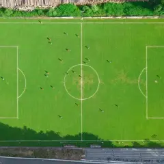 Boisko do piłki nożnej z zawodnikami. Widać linie boiska, bramki i środek boiska, co pozwala ocenić wymiary boiska do piłki nożnej.