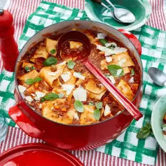 Herzhafte One Pot Lasagne in rotem Gusseisentopf, garniert mit Basilikum und Parmesan. Einfach und lecker!
