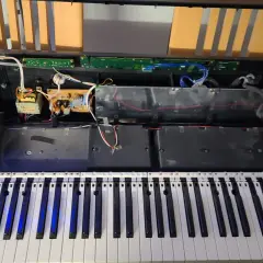Wnętrze keyboardu podczas naprawy instrumentów muzycznych. Widoczne głośniki, płytki drukowane i okablowanie.