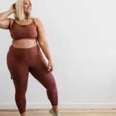 Kobieta plus size w brązowym komplecie sportowym, legginsy z kieszeniami.