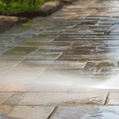 Hochdruckreiniger säubert ein Betonpflaster. Der Wasserstrahl entfernt Schmutz und lässt die Steine wieder wie neu aussehen.