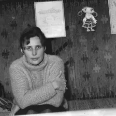 Młoda kobieta w swetrze siedzi na tle gobelinu. Na ścianie wiszą dyplomy i lalka. Czy to Agnieszka Osiecka, której prawdziwe nazwisko brzmi...
