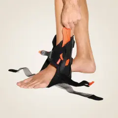 Eine Person legt eine wasserfeste Orthese am Sprunggelenk an. Sie bietet Halt und Stabilität.