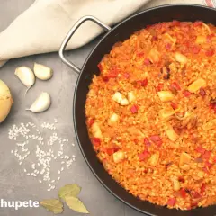 Arroz con calamares recién hecho en paellera, con ingredientes como cebolla, ajo y pimientos. ¡Un plato delicioso!