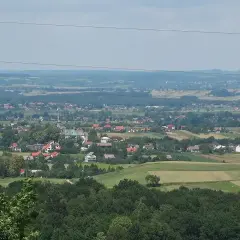 Widok na malowniczą wieś Przytkowice z kościołem w centrum, otoczoną zielonymi polami i lasami.