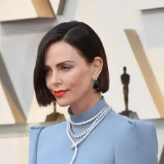 Charlize Theron con un elegante caschetto corto pari, orecchini pendenti e una collana scintillante.