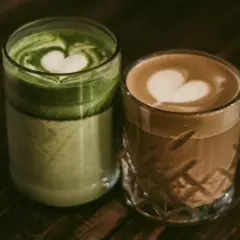 Dwa napoje w szklankach: zielona matcha i kawa z pianką w kształcie serca.