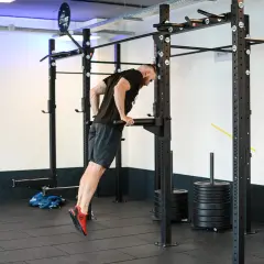Mężczyzna wykonuje ćwiczenie na dipy na triceps, angażując mięśnie ramion.