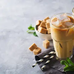 Dwa orzeźwiające freddo espresso z lodem, kostki brązowego cukru i listki mięty na szarym tle. Idealne na upalny dzień.