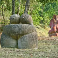 Esculturas de piedra en un museo al aire libre, evocando formas humanas en un entorno natural.