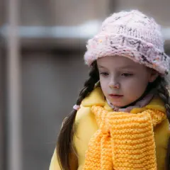 Smutna dziewczynka w żółtym płaszczu i różowej czapce, jak z serialu "Ukochane dziecko".