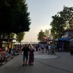 Skorzęcin atrakcje: tętniąca życiem promenada nad jeziorem, z ludźmi spacerującymi, siedzącymi na ławkach i korzystającymi z letnich rozrywek.