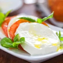 Frische Insalata Caprese mit saftigen Tomaten, cremigem Mozzarella und Basilikum, beträufelt mit Olivenöl. Ein Genuss!