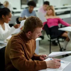 Studenci w sali wykładowej, skupieni na nauce. Nawet bez matury można rozpocząć studia, zdobywając wiedzę i nowe umiejętności.