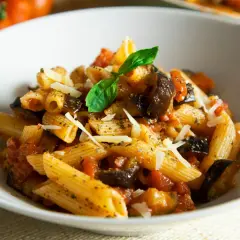 Penne z bakłażanem i pomidorami, posypane parmezanem. Proste danie włoskie, które zachwyca smakiem.